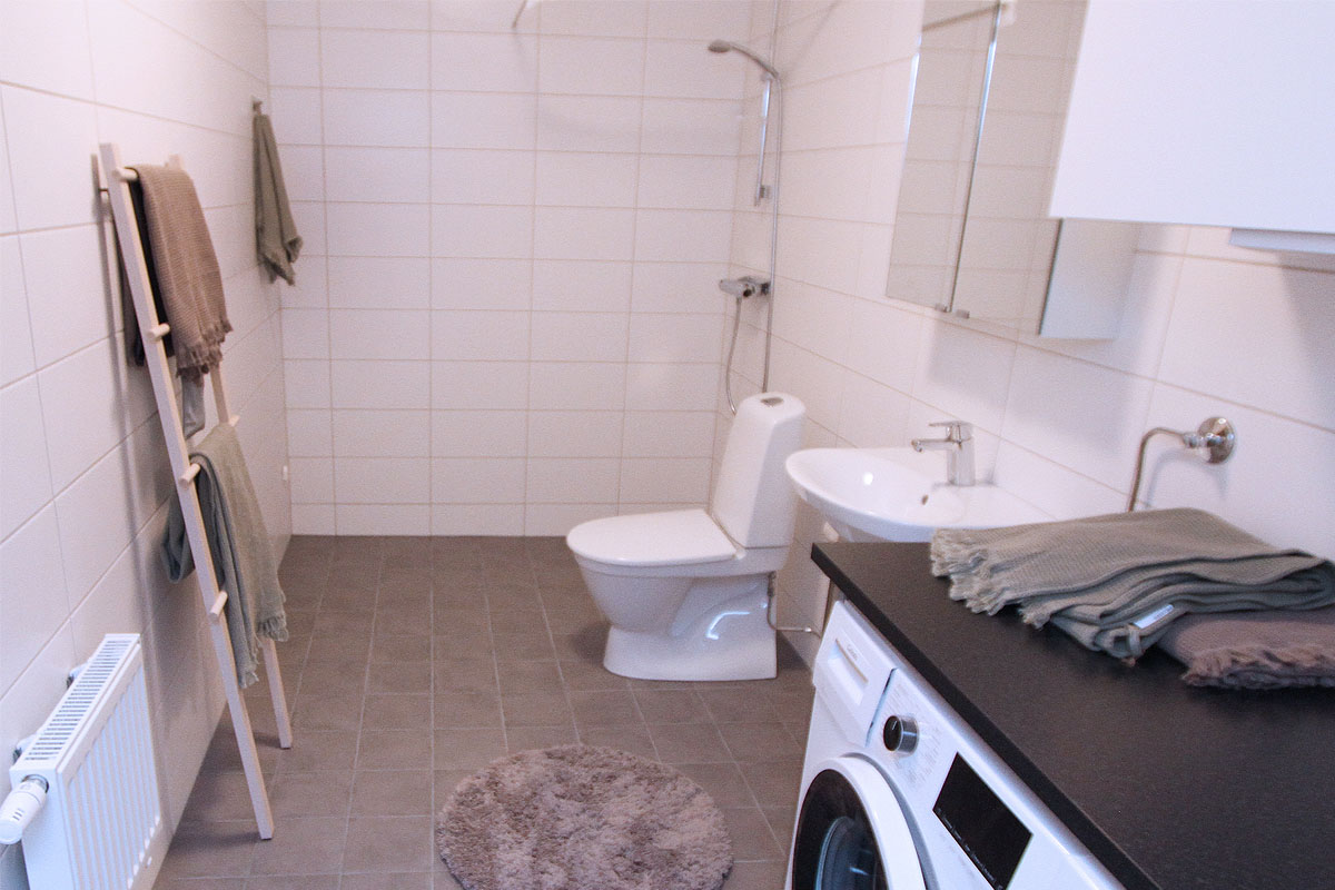 Helkaklat badrum med tvättmaskin och torktumlare i kvarteret Alabastern Tallhöjden.